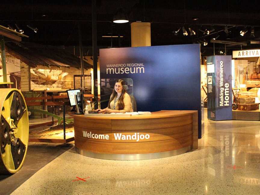Reception desk of wanneroo regional museum with attendant sitting at reception desk smiling invitingly.