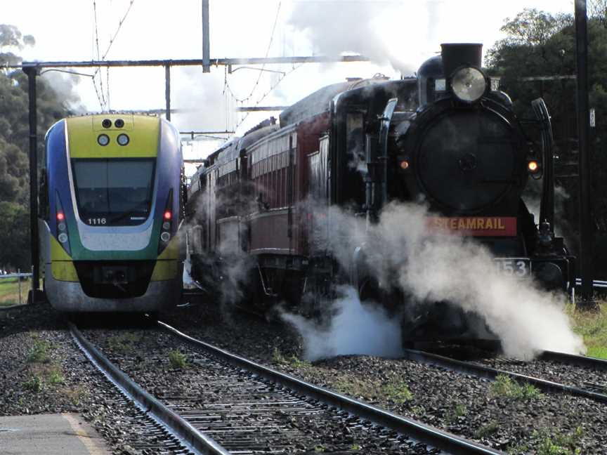 A VLinetrainspassesasteamlocomotiveat Pakenham
