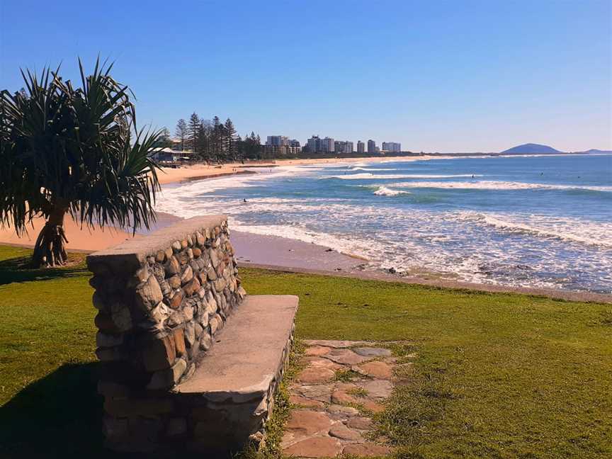 The view of people surfing at Alexandra Headland Beach with Mount Coolum in the background.