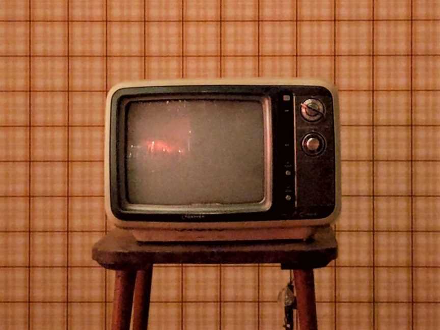Old-school TV against checked wallpaper.